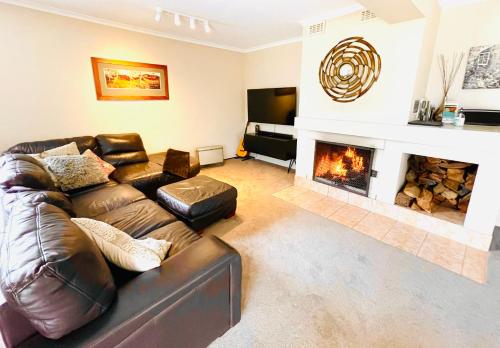 a living room with a leather couch and a fireplace at Full Circle Apartments in Jindabyne