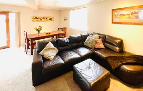 a living room with a leather couch and a table at Full Circle Apartments in Jindabyne