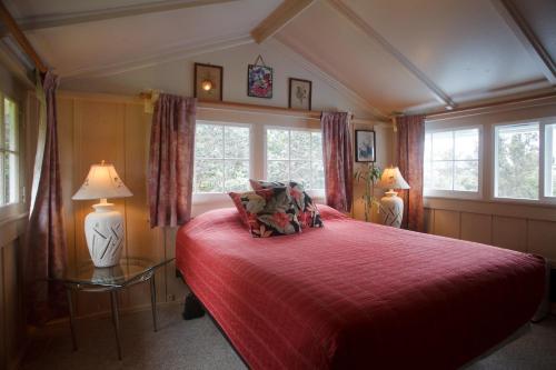 a bedroom with a red bed and two windows at Volcano Hale in Volcano