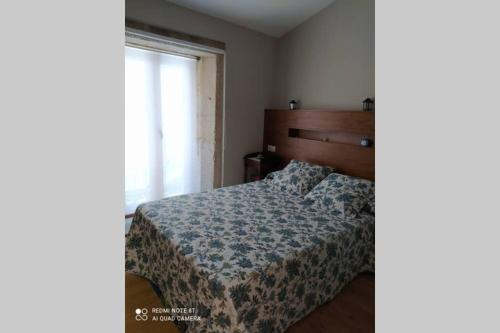 1 dormitorio con 1 cama con manta azul y ventana en Casa de piedra acogedora a 2 minutos de la playa en Laxe