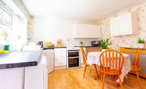 a kitchen with white cabinets and a table and chairs at Room near to Birmingham city centre with parking in Birmingham