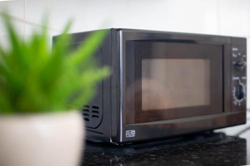 a microwave sitting on a counter next to a plant at Private room in Birmingham city centre with free parking in Birmingham