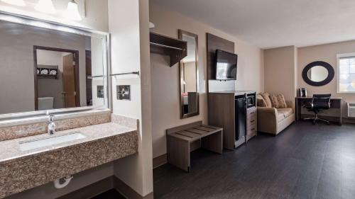 a bathroom with a sink and a living room at SureStay Plus Hotel by Best Western Kearney in Kearney