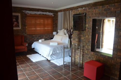 a bedroom with a bed and a brick wall at Mon Repos Guest Farm in Bela-Bela