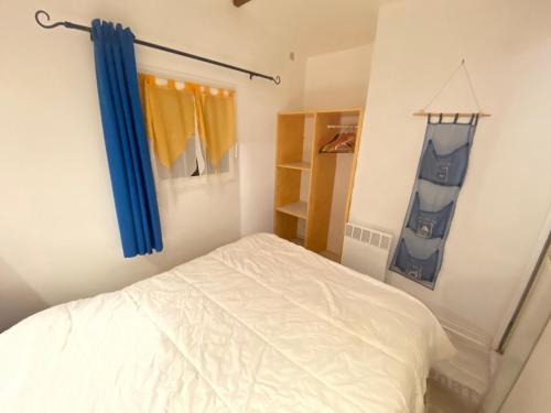 a bedroom with a white bed and a blue curtain at Mobilehome 3 chambres curistes camping piscine in Saint-Paul-lès-Dax