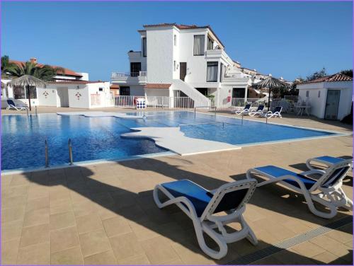 a swimming pool with two lawn chairs and a slide at Pebble beach apartamento, Amarilla golf in San Miguel de Abona