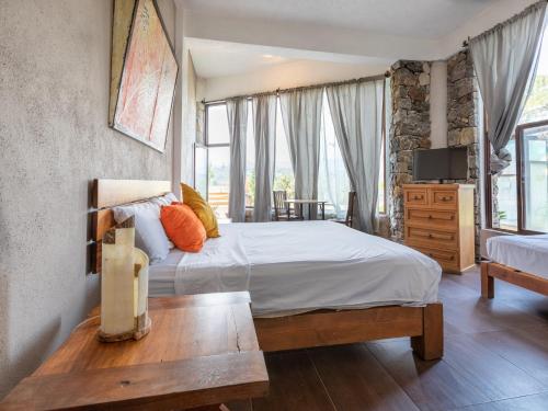 a bedroom with a bed and a table and a tv at Hotel Santa Rosa in Valle de Bravo