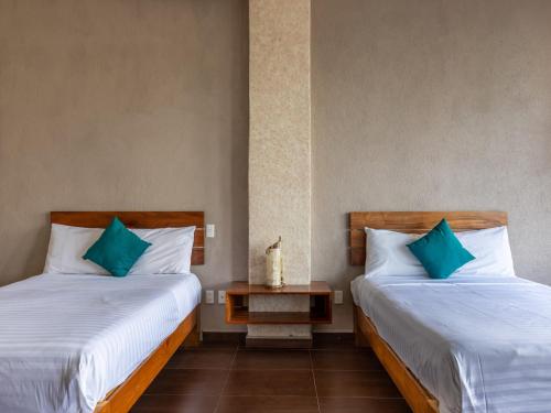 two beds with blue pillows in a room at Hotel Santa Rosa in Valle de Bravo
