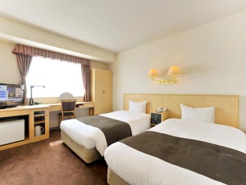 a hotel room with two beds and a television at Yamagata Kokusai Hotel in Yamagata