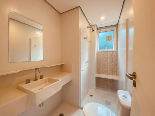 uma casa de banho branca com um lavatório e um WC em Vista Mágica na Praia de Camburizinho A em São Sebastião