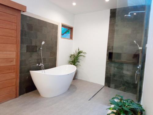 a bath tub in a bathroom with a shower at Bingin Pura Vida Villas in Uluwatu