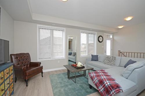 a living room with a couch and a chair at Royal Stays Townhome Collection - 3 Bedroom Townhome in Oakville in Oakville
