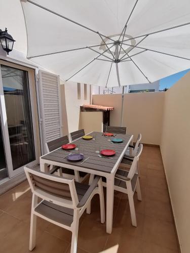 a wooden table with chairs and an umbrella at MORADIA DO SOL in Olhão