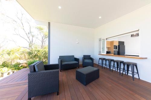 a living room with chairs and a table and a kitchen at Sea Haven in Old Bar