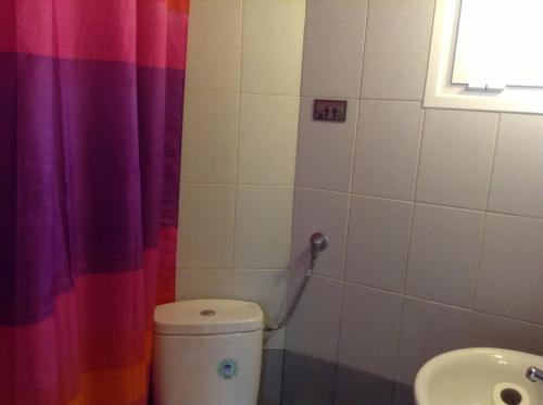 a bathroom with a toilet and a rainbow shower curtain at Studios LaLu in Skiathos