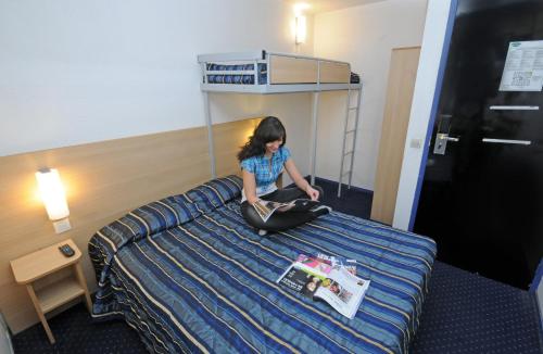 a young girl sitting on a bed in a hotel room at Mister Bed Lomme in Lomme