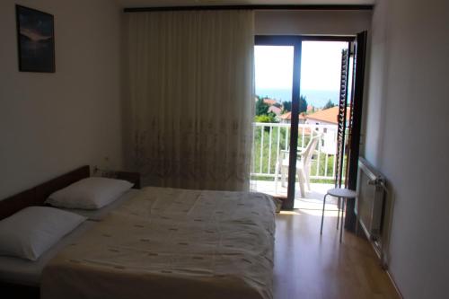 1 dormitorio con 1 cama y puerta a un balcón en Rooms Amfora, en Krk