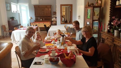 Eine Gruppe von Menschen, die an einem Tisch sitzen und Essen essen. in der Unterkunft Le Pré Fleuri in Curlu