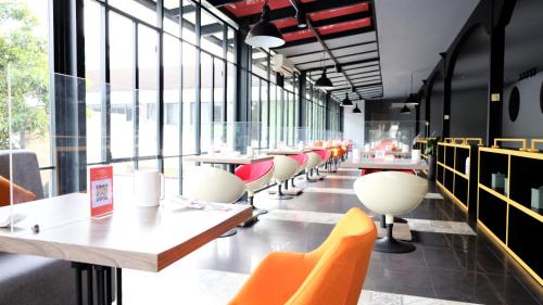 ein Restaurant mit Tischen, Stühlen und Fenstern in der Unterkunft Moritz Hotel RSAB Harapan Kita in Jakarta