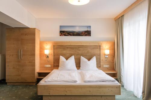a bedroom with a bed with white sheets and pillows at Familienhotel Botenwirt in Kleinarl
