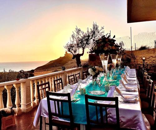 a long table with a blue table cloth and chairs at La Collina sul Mare in Palma di Montechiaro