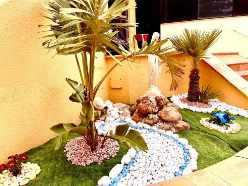 a table with two palm trees and rocks on the ground at La Collina sul Mare in Palma di Montechiaro