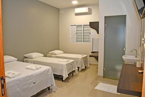 a hospital room with three beds and a sink at Hotel Alphard in Várzea Grande