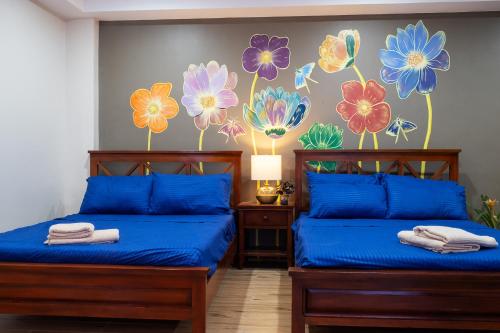 two beds in a room with flowers painted on the wall at Luis miguel's place in Dumaguete