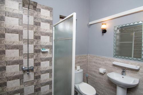 a bathroom with a toilet and a sink and a shower at Amaan Beach Bungalows in Nungwi