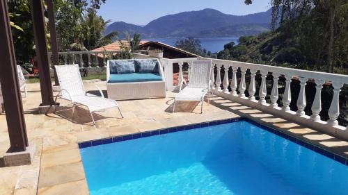 a swimming pool with two chairs and a table at Recanto J&R in Angra dos Reis