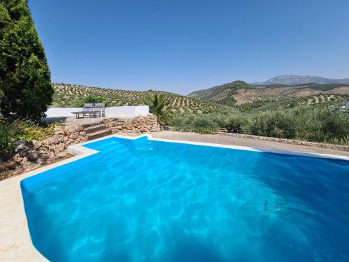 a blue swimming pool with mountains in the background at Cortijo Las Rodrigas in Sabariego