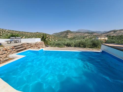 una piscina blu con montagne sullo sfondo di Cortijo Las Rodrigas a Sabariego