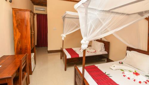 a room with two beds and a desk and a bedroom at Amaan Beach Bungalows in Nungwi