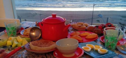a table with a red tea pot and plates of food at Appartement plage mehdia in Kenitra