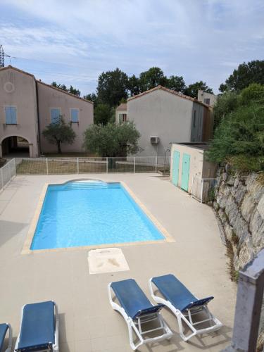 una piscina con 2 tumbonas y un par en Maisonnette dans domaine avec piscine à Nyons, pays des olives, en Nyons