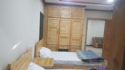 a bedroom with a bed and a wooden closet at Zujaja Guest House in Bhurban