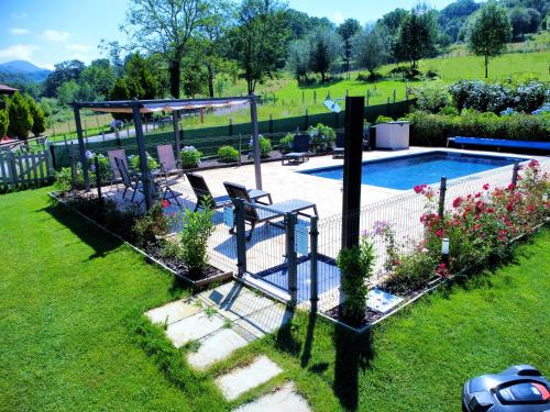 a swimming pool in a yard with chairs and flowers at Complejo Turístico Les Cotolles in Cangas de Onís