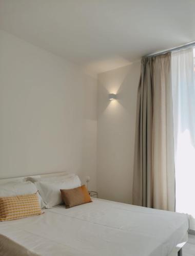Cama blanca en habitación con ventana en Ostro - Guest House, en Agrigento