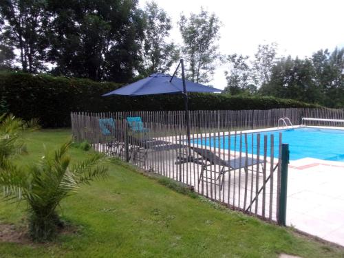 una valla con sombrilla junto a la piscina en cheztitoine, en Pouzauges