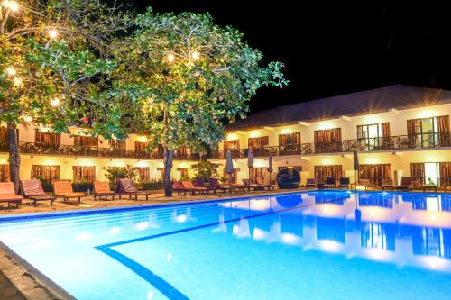 a pool in front of a hotel at night at Amaan Beach Bungalows in Nungwi
