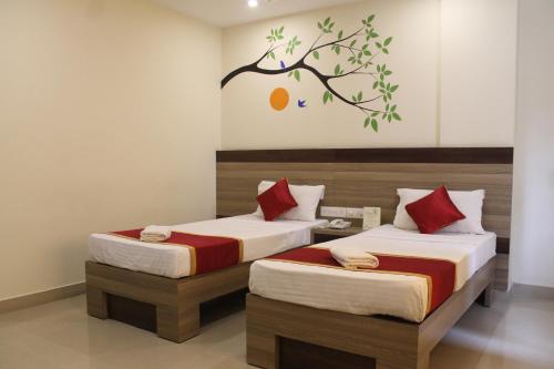 een slaapkamer met 2 bedden en een boom aan de muur bij HOTEL GREEN TREES in Bangalore