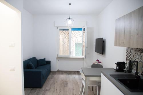 uma sala de estar com um sofá azul e uma cozinha em Appartamento il Mulino em Orbetello