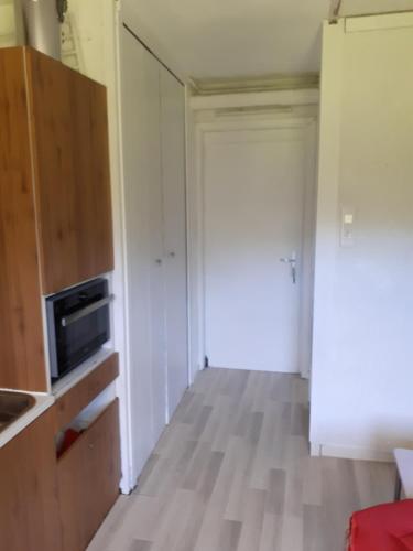 a room with a kitchen with a microwave and a door at Studio sur les pistes in Villard-de-Lans