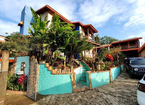 ein Haus mit einer blauen Wand mit Bäumen und Pflanzen in der Unterkunft Pousada Natureza e Arte in Cunha