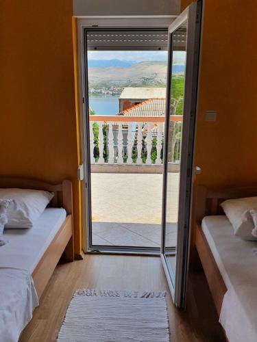 a room with two beds and a door to a balcony at Apartments Adriapag in Pag