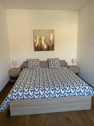a bedroom with a large bed with a blue and white bedspread at L’appartement de Rose in Seurre