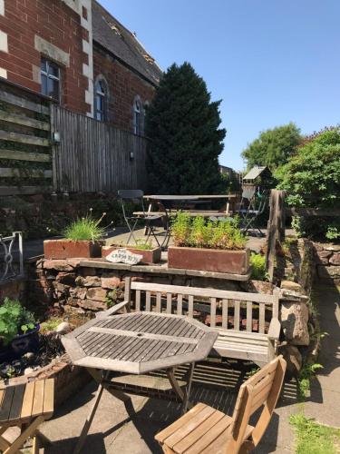 a patio with a table and a bench in a yard at The Cross Keys in Kippen in Kippen
