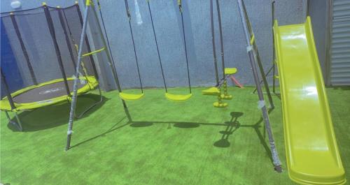 a group of swings in a playground with grass at شاليه دانة بحر in Yanbu