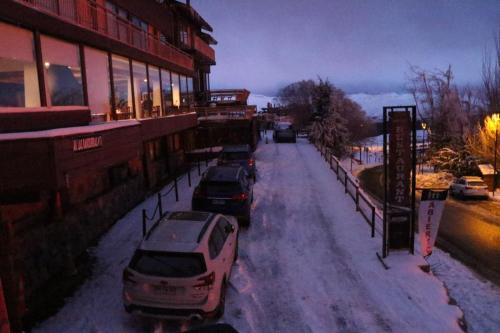 a snow covered street with cars parked next to buildings at Hotel HF in Farellones