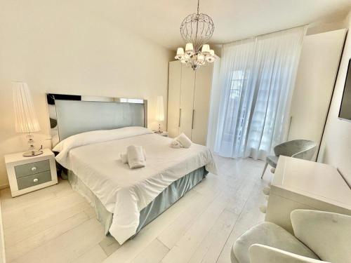 a bedroom with a large white bed and a chandelier at Luxury Home Paradise View in Forte dei Marmi